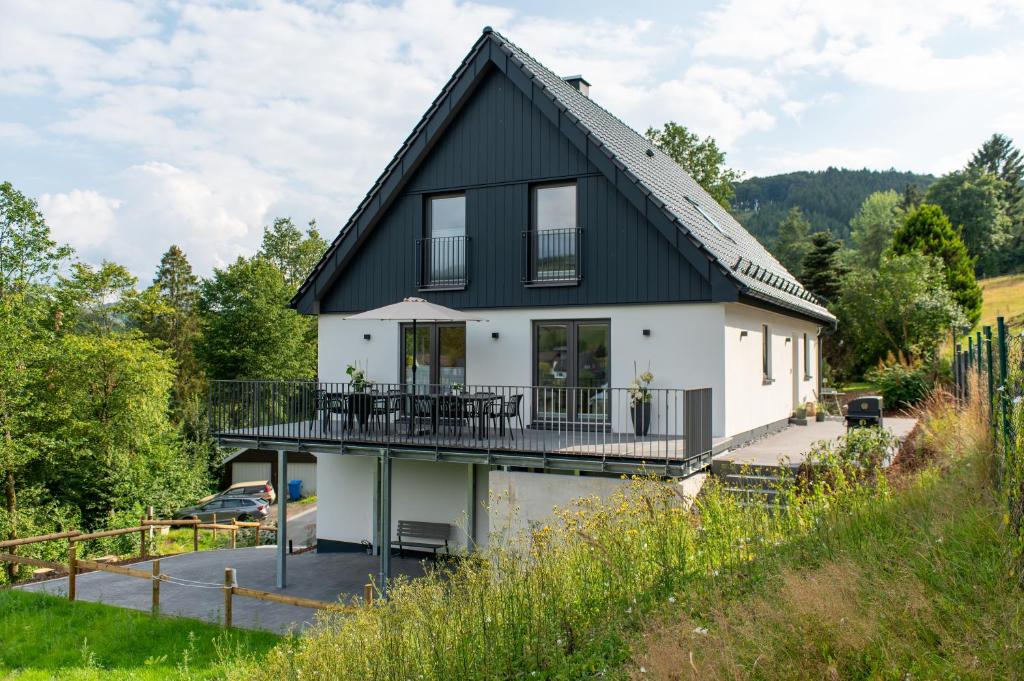 a house with a black roof and a balcony at Eickhagen Nº7 - 10 Personen - 5 Schlafzimmer - 220qm - 4 Badezimmer - Wellness - Sauna in Olsberg