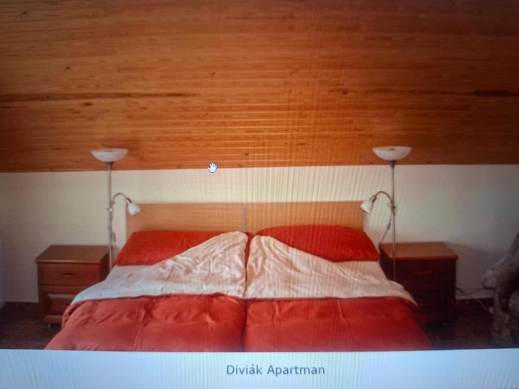 a bedroom with a red bed with two lamps at Diviák Apartman in Zalaszentmihály