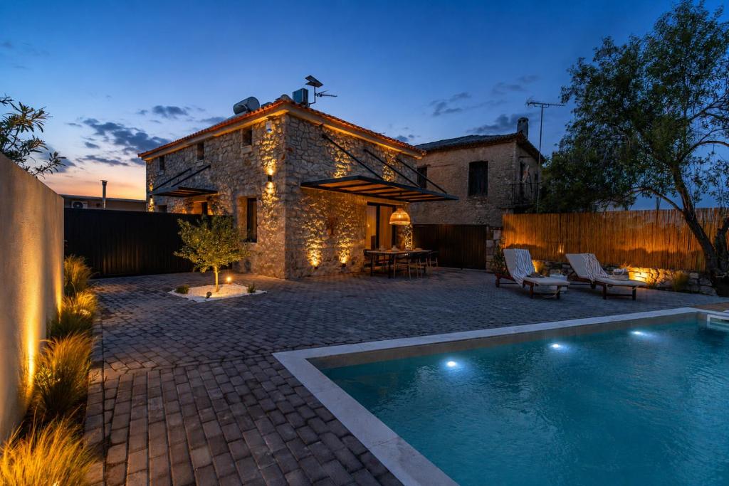 a backyard with a swimming pool in front of a house at Olea Stone Villa in Pylos