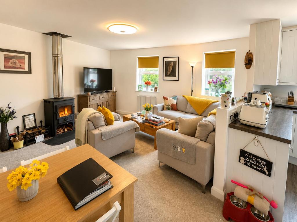 a living room with couches a table and a kitchen at Muddy Boots Scarpa in Kirkby Stephen