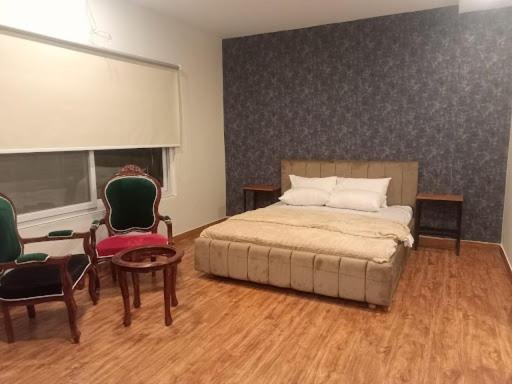 a bedroom with a bed and two chairs and a table at White Ice Cottages in Mānsehra