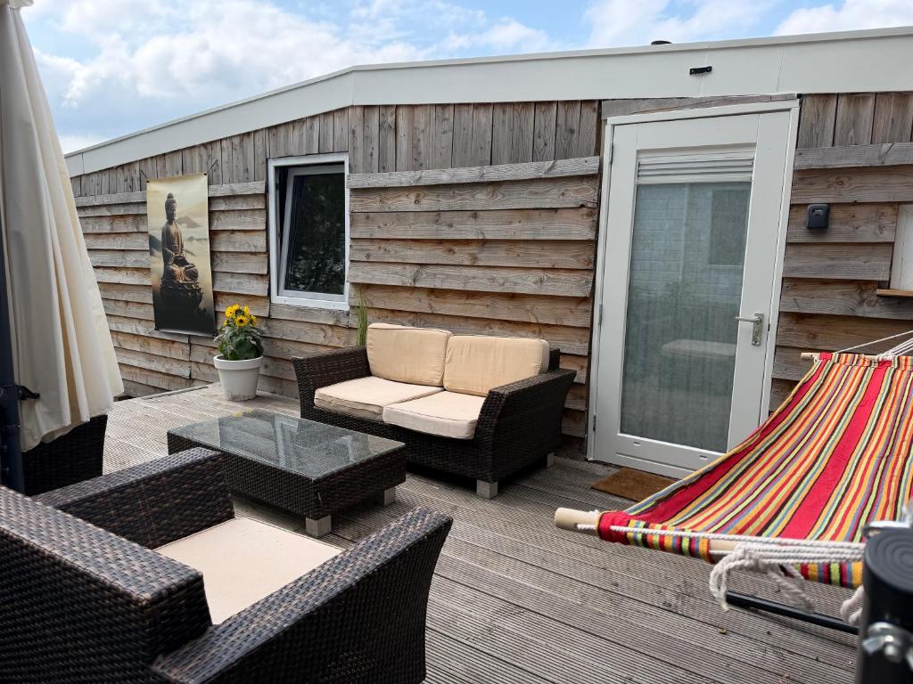 a patio with chairs and a hammock on a deck at Knus houten huisje bij het bos in Anloo