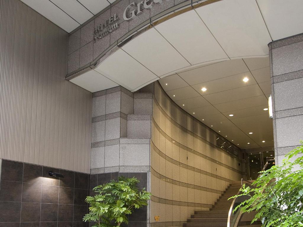 a lobby of a building with stairs and plants at Hotel Premium Green Plus in Sendai