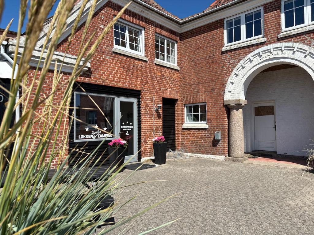 a brick building with an archway and a door at Løkken Family Camping & Guesthouse in Løkken