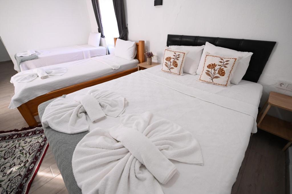 two beds in a room with white sheets and pillows at Rijeka Pansiyon in Ayvalık