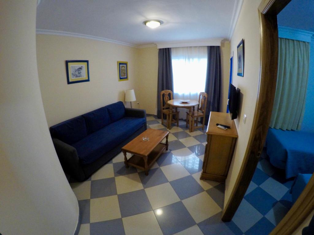 sala de estar con sofá azul y mesa en Apartamentos Niña de Oro, en Torremolinos
