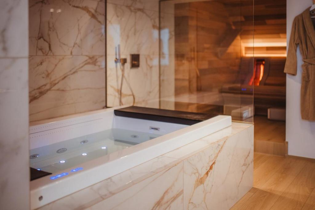 a large bathroom with a tub with a glass wall at L'exclusif douceur in Aubel