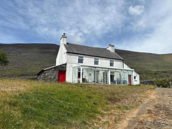 a white house sitting on top of a hill at Glenmore Cottage - Waterville in Waterville