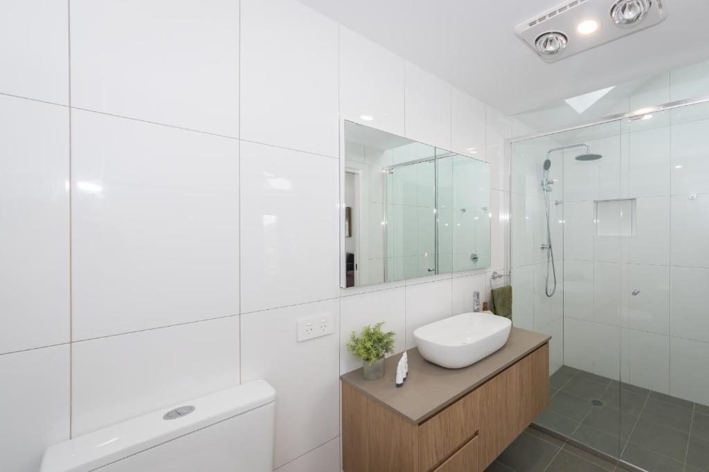 a white bathroom with a sink and a mirror at Breakwall Retreat in Manning Point