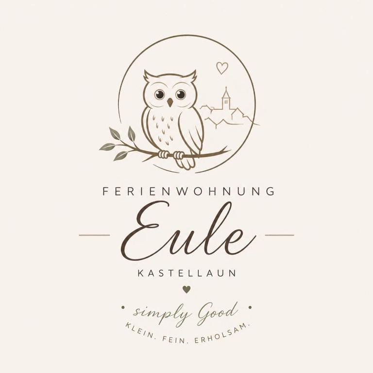 an owl sitting on a branch in a round frame with the inscription enchanting elite at Ferienwohnung Eule in Kastellaun