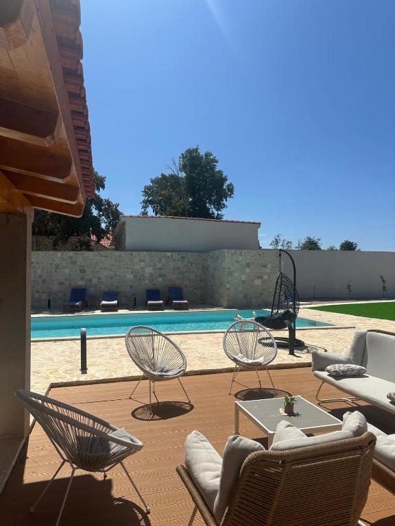 a patio with chairs and tables and a pool at Hidden Villa in Klarići