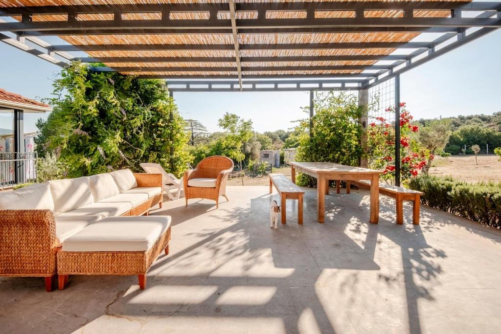 a patio with wicker furniture and a wooden pergola at Rustic Stone House with Spacious Terrace 2BR in Burhaniye