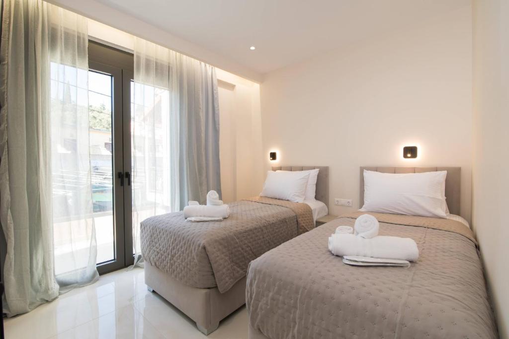 two beds in a hotel room with towels on them at Glamour Residences 5-6 by CorfuEscapes in Análipsis