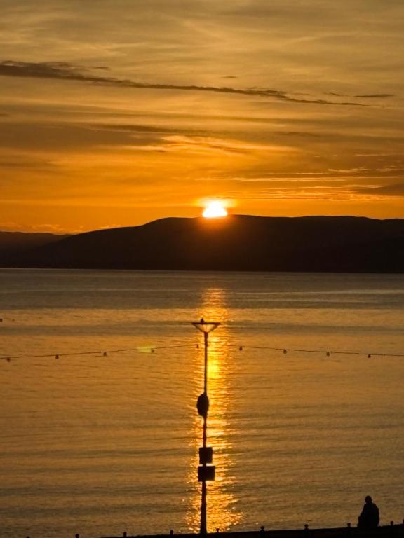 a sunset over a body of water with a light pole at Skips in Largs