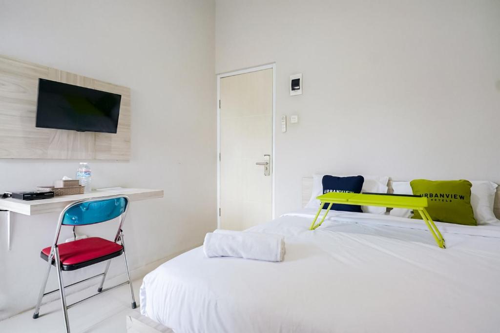 a bedroom with two beds with a desk and a chair at Urbanview Hotel Bari Syariah Palembang By RedDoorz in Sukarami
