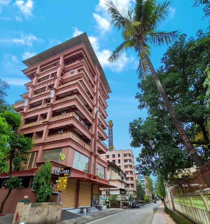 a tall building with a palm tree next to a street at Lions Hotel Adidev in Badlapur