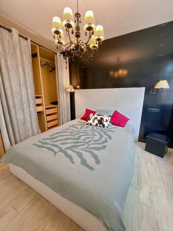 a bedroom with a large bed with a chandelier at Zen & uS Maison entière in Margny-lès-Compiègne