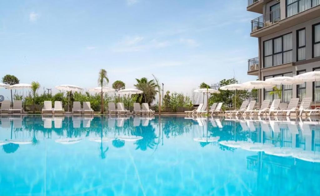a swimming pool with chairs and umbrellas next to a building at Laristone Suite Spa Hotel in Antalya