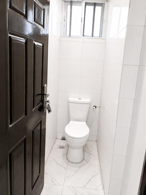 a bathroom with a white toilet and a black door at Aaron Obibi Court in Owerri