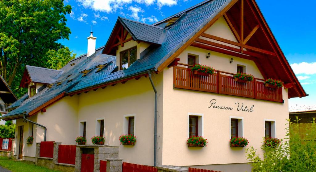 a house with a blue roof and flowers on the windows at Penzion Vital in Liberec