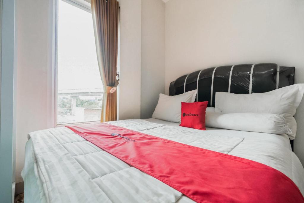 a bedroom with a large bed with a red blanket at RedDoorz Plus near Palembang Airport 3 in Palembang