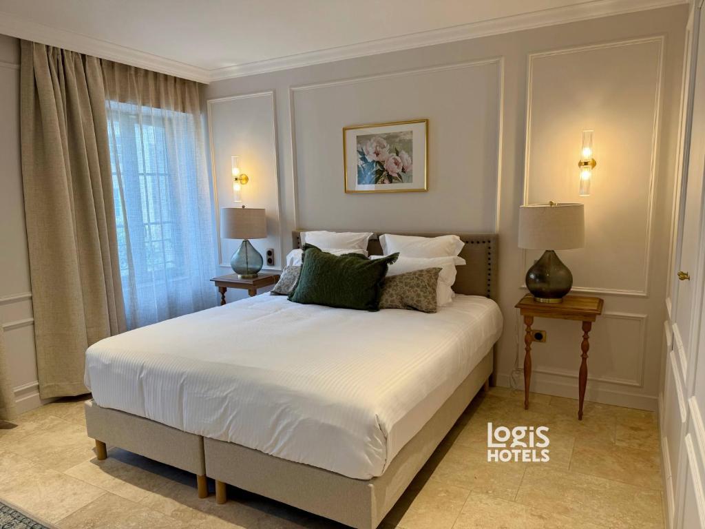 a bedroom with a white bed with two tables and a window at Logis Hôtel Maison Turenne in Martel