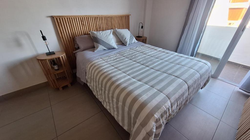 a bed with a striped blanket in a bedroom at Apart Z Alberdi in Belén de Escobar