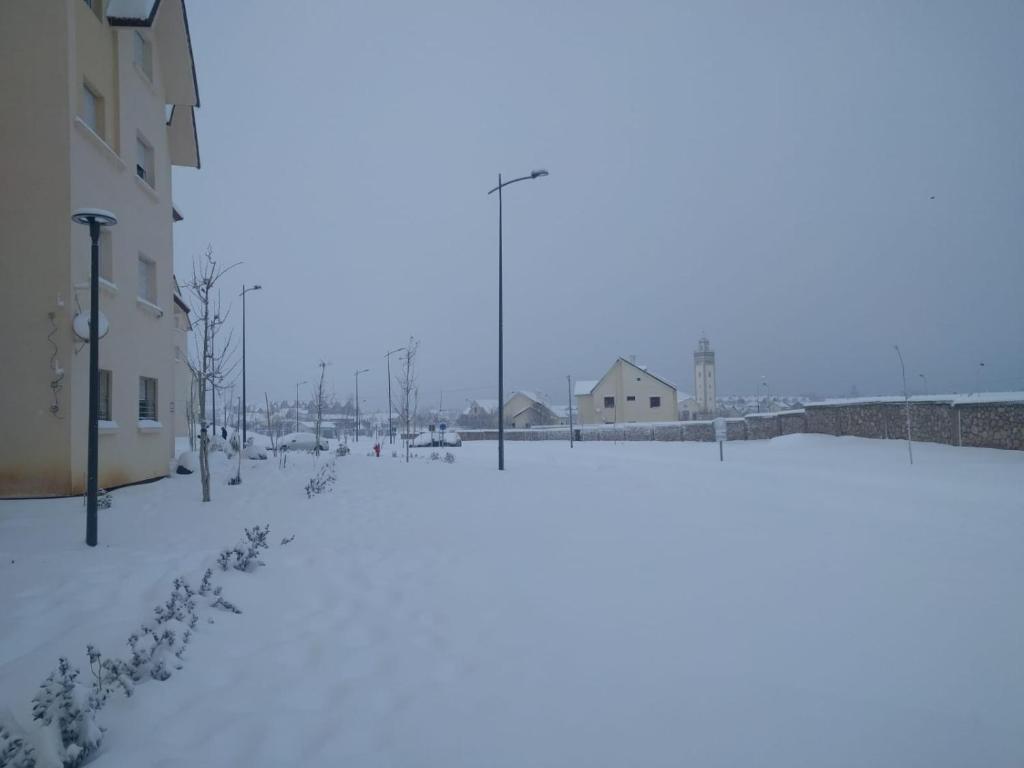 a snow covered street with buildings and houses at App2 in Ifrane