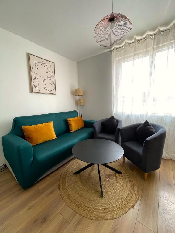 a living room with a green couch and a table at Trois Merlettes in Schiltigheim