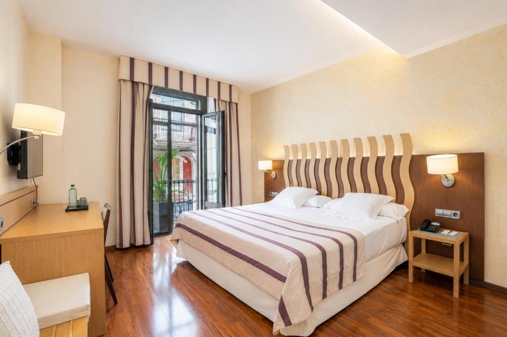 ein Hotelzimmer mit einem großen Bett und einem Fenster in der Unterkunft Hotel Duran in Figueres