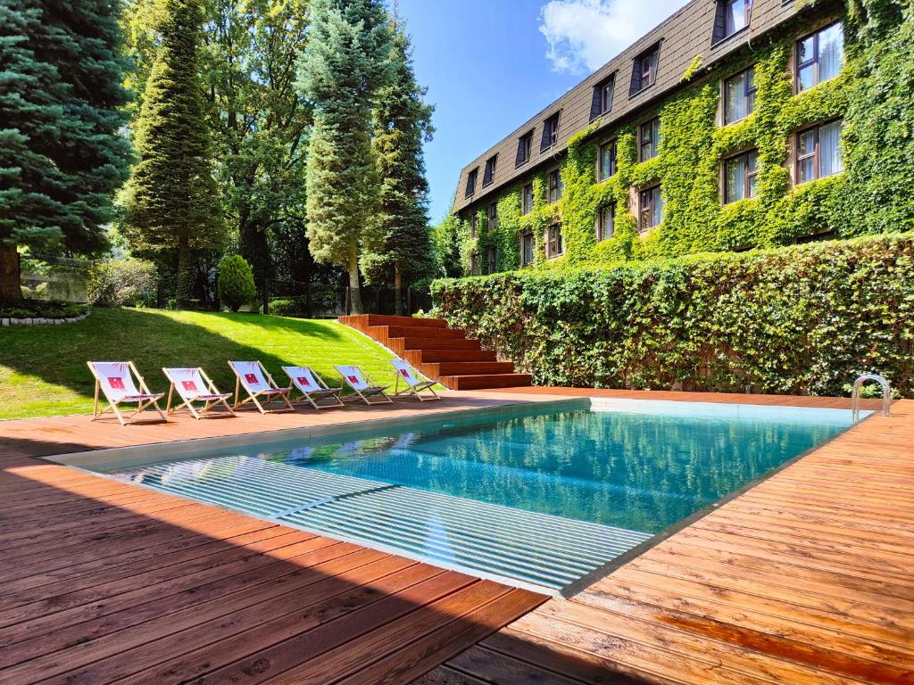 a swimming pool with chairs and a building at Booking Hotel & Spa in Krakow