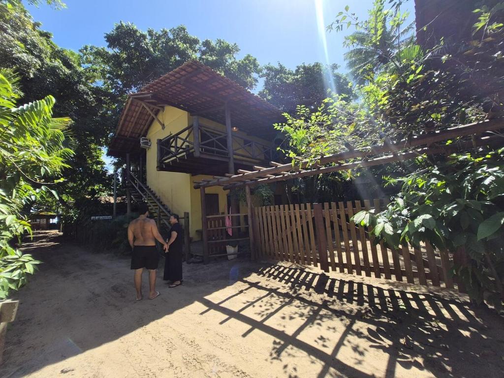 two people standing in front of a house at Pousada Encanto do Mutá in Barra Grande