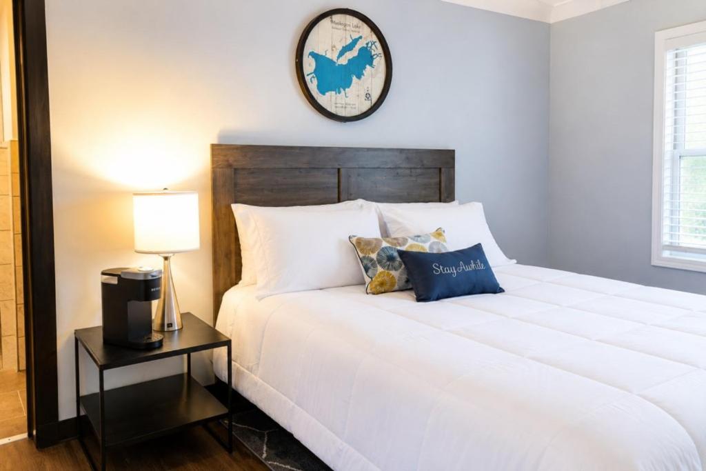 a bedroom with a large white bed with a clock on the wall at Cozy Updated Queen Ground Floor Studio in Muskegon