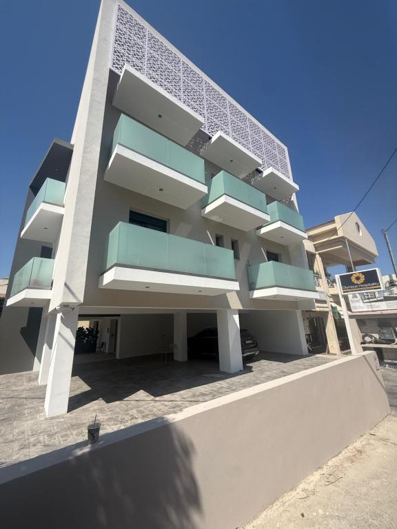 a large white building with blue balconies on it at Olympus Hospitality Rhodes in Rhodes Town