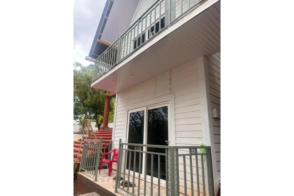 a house with a balcony and red chairs at FabHotel Hill View Cottages in Arpora