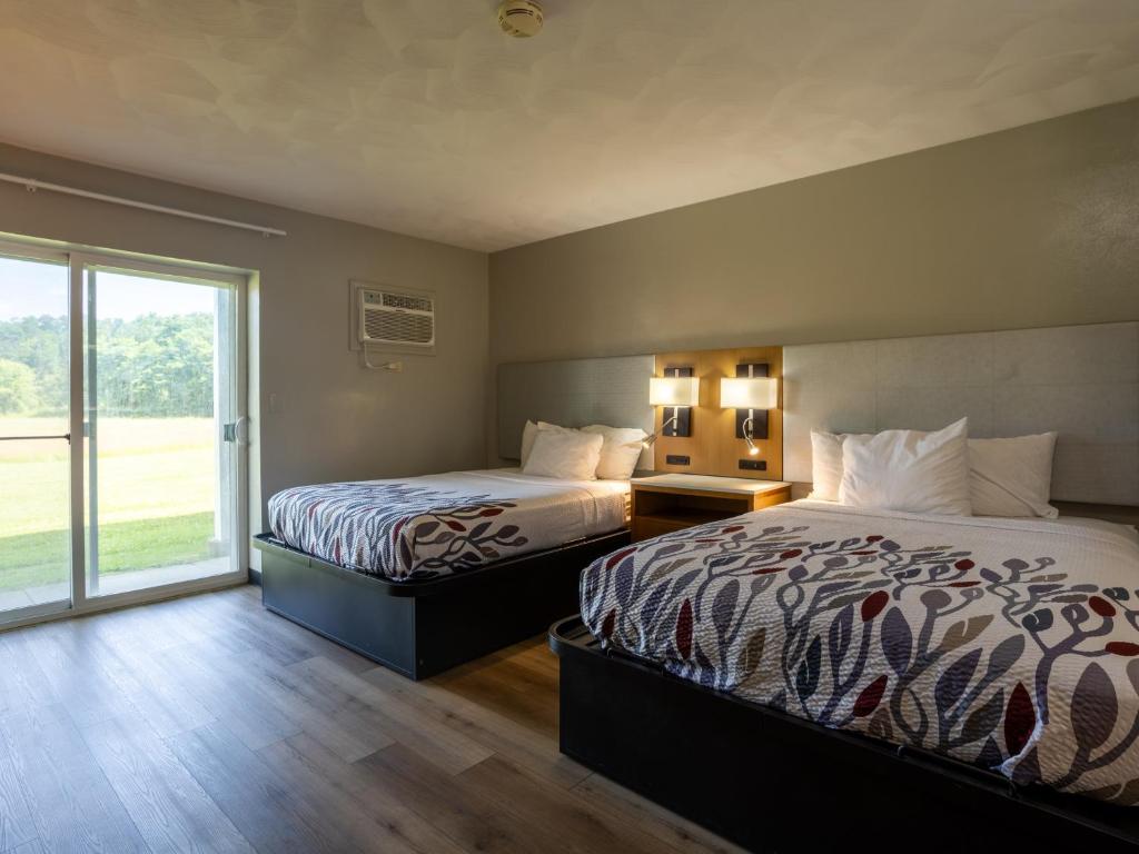 a hotel room with two beds and a large window at Colonial Brick Inn & Suites in New Milford