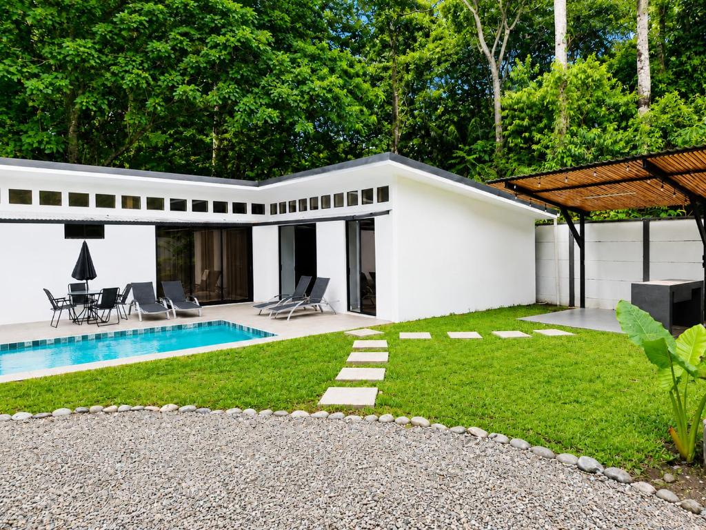 a white house with a swimming pool and a yard at Villa Isora in Talamanca