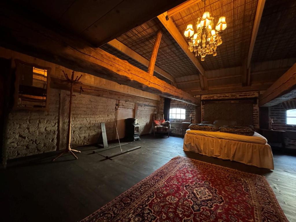 a large room with a bed and a chandelier at Anno 1782 Unique Romantic Glamping at the Manors Historic Barn in Arnager