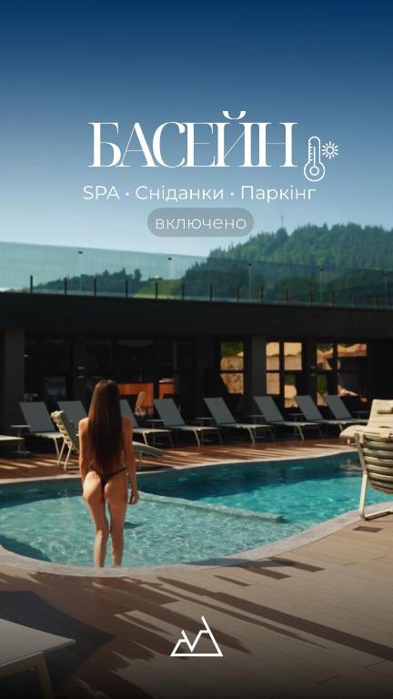 a woman in a bikini walking into a swimming pool at VILSON hotel in Bukovel