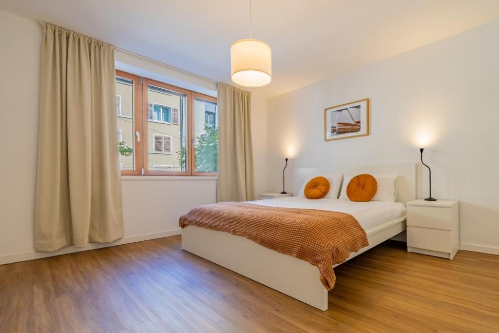 a bedroom with a bed with orange pillows and a window at Pure living Apartment in Zürich Oerlikon in Zurich