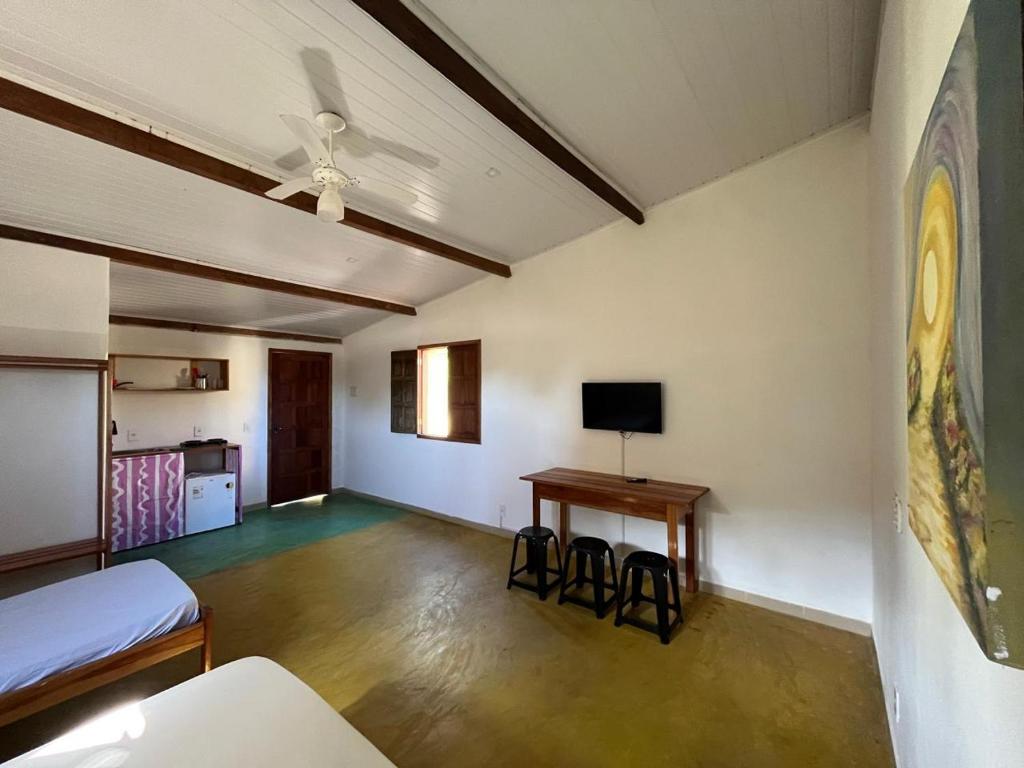 a room with a bed and a table and a tv at Pousada Fanticelli in Nova Viçosa