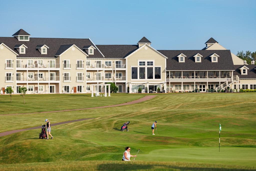 a group of people playing golf in front of a large building at Rodd Crowbush Golf & Beach Resort in Morell