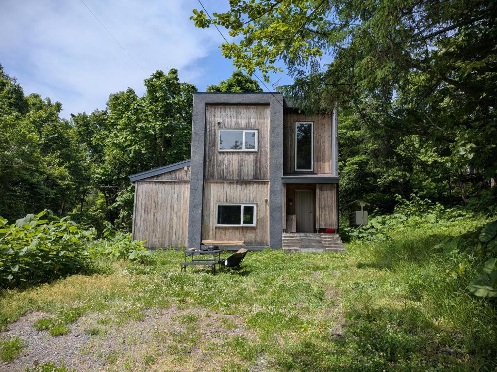 a small wooden house in the middle of a field at The Bunker at Yunosato in Rankoshi