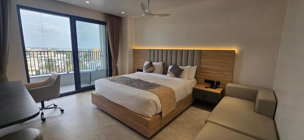 a bedroom with a bed and a large window at Hotel Kalyani Landmark in Elūru