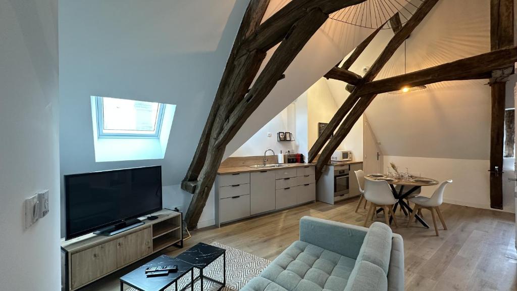 a living room with a couch and a tv and a table at L'ombrelle in Chablis