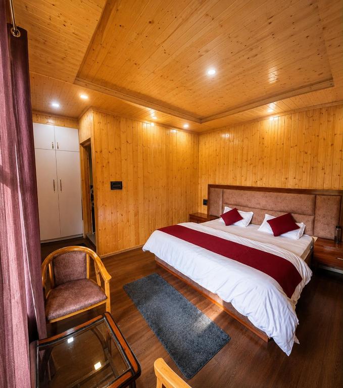 a bedroom with a large bed and a chair at Harshil wood stay in Harsil