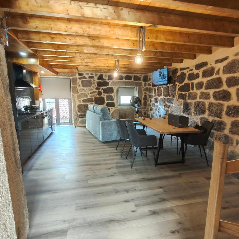 a living room with a table and a stone wall at Casa Fornos de Amor in Fornos de Algodres