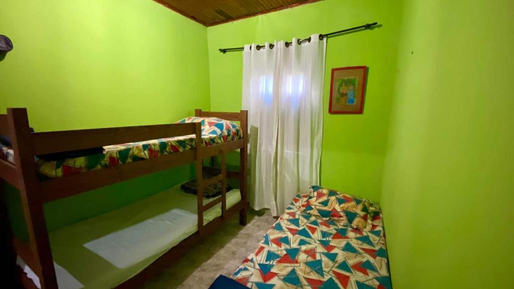 a green room with two bunk beds in it at Quarto Alecrim in Ibicoara