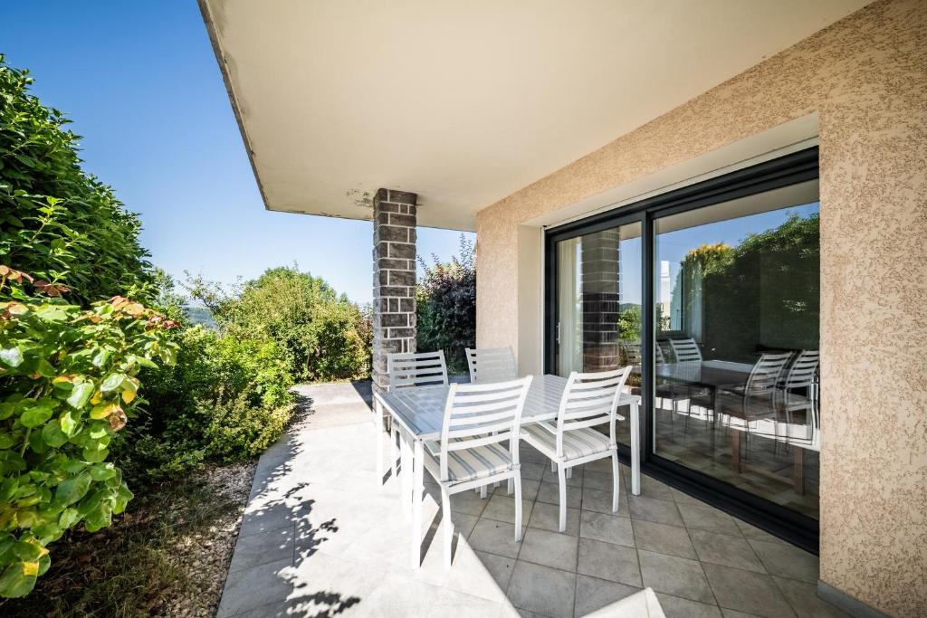 a patio with white chairs and a table on a balcony at Gîte Du Noiret in Cruseilles