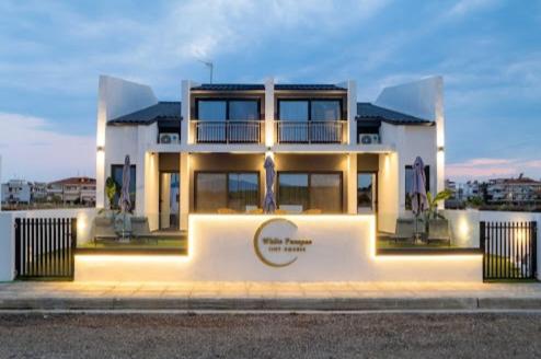 a large white house sitting on the side of a street at White Pampas Tiny Houses 1 in Paralia Dionysiou